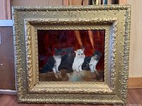 Full view of the ornate gold frame and the glass painting of four cats sitting together against a reddish-brown background.