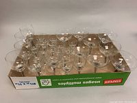 Multiple clear glass wine glasses with blue stems arranged on a cardboard box, showing a range of sizes and bowl shapes.