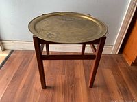 Front view of the wooden stand with removable round engraved brass tray showing patina and water stains