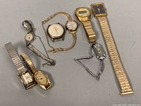 Overview photo showing eight vintage ladies wristwatches in various conditions, including metal band styles in gold and silver tones.