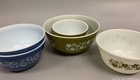 Set of five Pyrex mixing bowls arranged in two groups showing Spring Blossom and Colonial Mist designs.