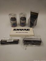 All items arranged showing packaging and contents including the Shure Stylus Force Gauge, L'art du Son cleaning liquids, Mobile Fidelity brush, and anti-static brushes