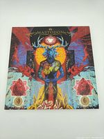 Front cover of Blood Mountain album by Mastodon on vinyl record showing colorful fantasy artwork with blue deer figure and abstract shapes.