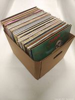 Cardboard crate full of 12" vinyl LPs with Queen News of the World visible at front