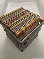 Plastic crate filled with vinyl records, spines facing upward showing some artist and album names