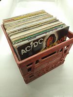 Plastic crate filled with around 40 vinyl records, visible album covers on top including AC/DC Powerage