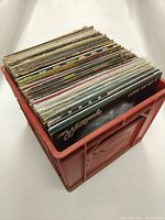 Red plastic crate filled with vinyl LPs, angled view