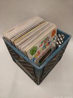 Photo of a blue plastic milk crate filled with a collection of 12-inch vinyl records.
