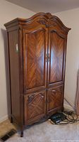Full front view of armoire showing overall design, doors, and carved crown