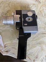 Side profile of the Yashica 8mm movie camera, showing black body with grip, viewfinder, and lens mount