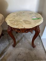 Front and top view of the French provincial side table showing marble top and ornate wooden legs.