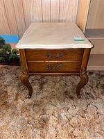Front view of Craftline side table showing stone top, two drawers with metal handles, and cabriole legs with casters.