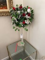 Tall glass vase with faux flower bouquet containing red and white roses and greenery.
