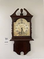 Full frontal view of Bulova wooden wall clock hanging on wall, shows overall design and shape.