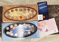 Two Canadian Millennium quarter sets and two other commemorative quarters in original packaging shown on a wooden surface.