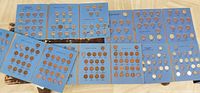 Blue coin folders laid out showing partial sets of Canadian pennies, nickels, dimes, and quarters in circulated condition.