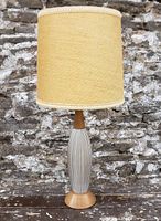 Full front view of lamp with burlap shade in front of stone wall