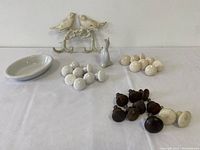 Overview of all items laid out on white cloth: antique ceramic pie bird, cast metal bird double hook, 8 white porcelain pulls, 8 cream crackle-glazed porcelain pulls, 10 wooden pulls in dark and white colors.