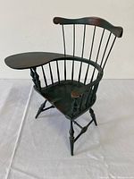Side angle showing the overall form, dark wood finish, and attached writing arm of the miniature Windsor chair.