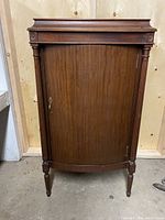 Front view of the antique wooden music stand cabinet showing full height and rectangular top with door.