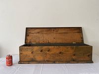 Front view of open wooden box showing interior and lid hinges, with a soda can for scale.