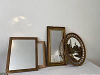 All four mirrors grouped together, showing variety of frames and painted scene on oval mirror.