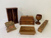 Seven wooden decorative and functional items including three boxes with lids, goblet, napkin holder, and two utensil trays.