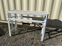 White painted rattan hallway table with glass top, showing front and side detail.