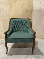 Front view of green tufted accent chair with wood frame