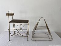 Front view of vintage brass and gold tone side table with magazine rack and separate triangular magazine holder placed side by side.