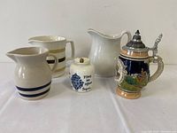 Includes four vintage pitchers and one ceramic beer stein with metal lid marked Berlin, West Germany.