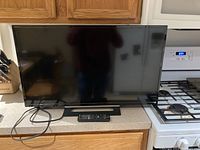 Front view of the Sony monitor with power cord and remote placed on kitchen counter.