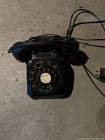 Top-down view of the antique rotary dial telephone showing the dial, handset, and worn surface.