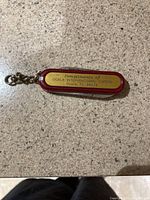 Top-down photo of the small Swiss Army knife keychain showing the label with 'Compliments of Ocala Interventional Cardio, Ocala, FL 34474' printed on it, placed on a granite countertop.