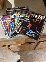 Six vintage comic books including Daredevil, Iron Man, and G.I. Joe in protective sleeves, showing worn condition