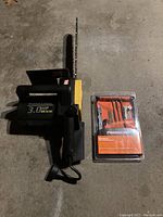 Photo of McCulloch electric chainsaw with visible bar and chain, placed on concrete floor alongside unopened sharpening kit in packaging.