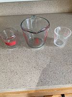 Three measuring glasses side by side showing relative sizes and markings