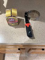 Oil filter in box next to the clamp tool on a counter.