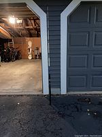 Fishing rod leaning against a house exterior next to a garage entrance, showing full length and context for size.