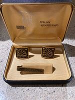 Open box showing gold-tone square cufflinks and matching tie clip with ornate Italian Renaissance design inside original Swank box