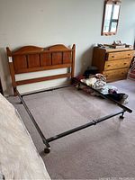 Full view of the solid wood headboard attached to black metal bed frame on caster wheels in bedroom.