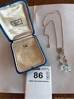 Opened blue velvet Birks box with interior satin lining and spring ring clasp cable chain laid beside lot card