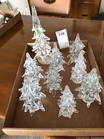 Set of nine clear blown glass Christmas trees in a cardboard box, eight smaller and one larger tree visible