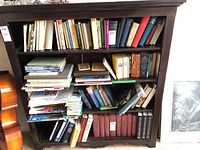 Wood bookcase filled with old books and magazines on four shelves showing structural condition and typical use.
