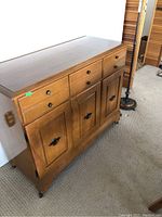 View of the buffet showing the front with three drawers above two cupboard doors, medium brown wood, traditional metal handles, minor surface wear on wood.
