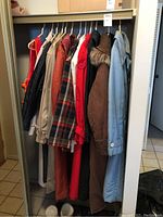 Photo of assorted ladies coats hanging on rack showing variety of colors and styles including fur trim, plaid, solid colors.