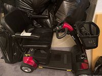 Side view of red and black GoGo Sport mobility scooter showing seat, armrests, wheels