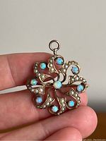 Front view of the brooch pendant held between fingers