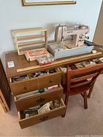 Photo of White brand sewing machine model 262 on a wooden sewing desk with drawers open containing assorted sewing notions and fabric scraps. Chair is included. Foot pedal on side.
