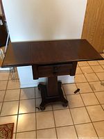 Front view of the small drop leaf table with drawer and pedestal base